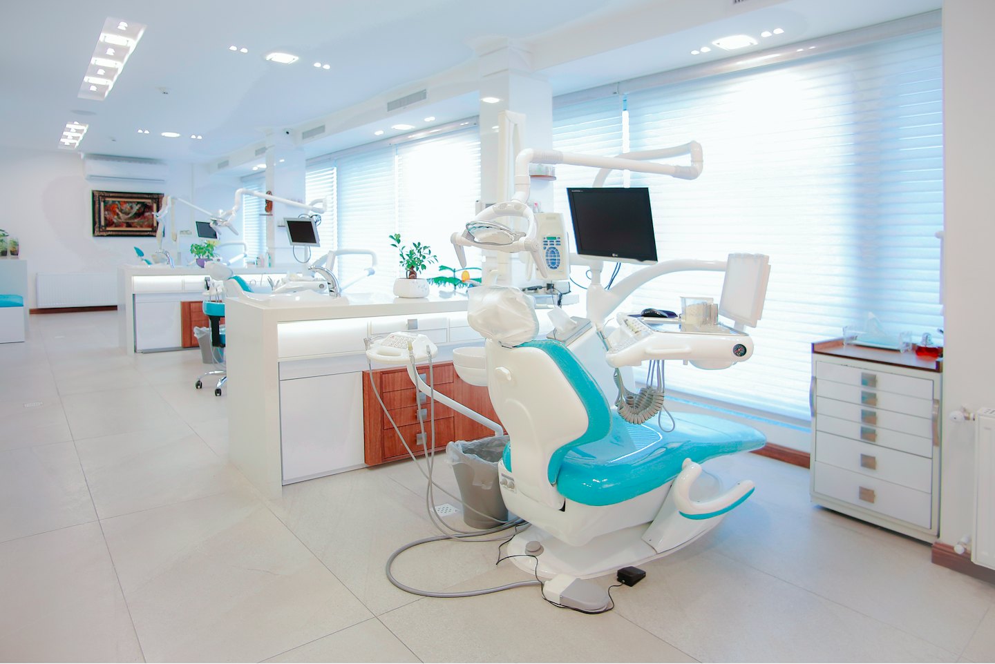 Modern dental clinic interior with turquoise and white chairs.