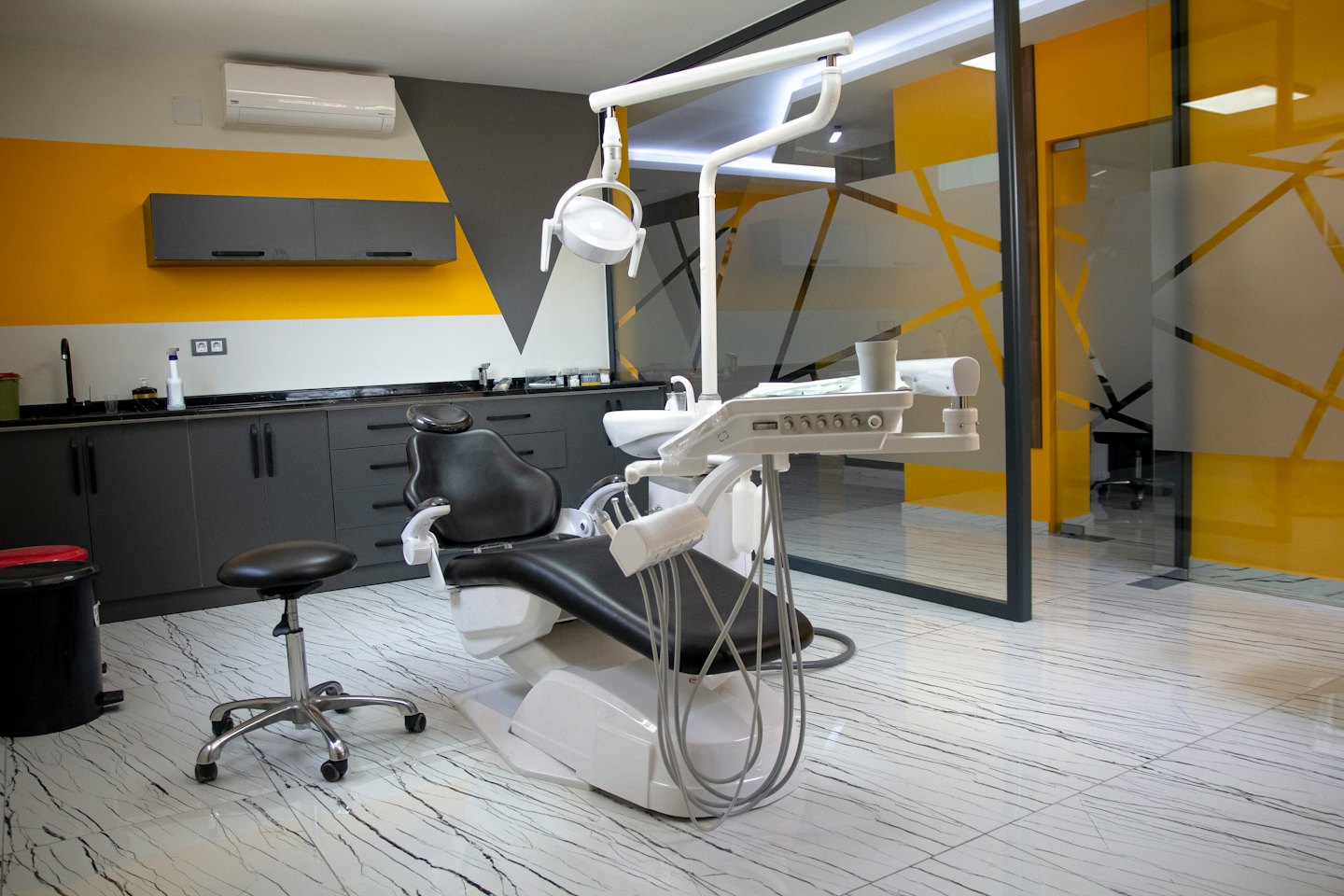 Empty dental treatment room with modern equipment and yellow wall.