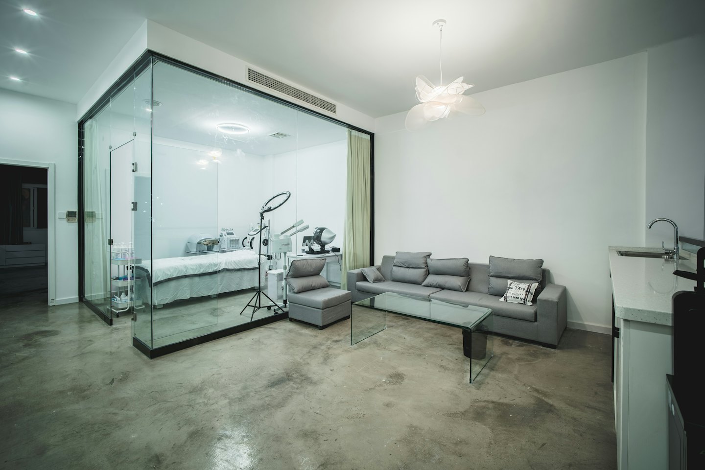 Modern spa waiting area and treatment room with white bed.